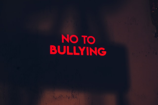 Uma placa vermelha em um fundo preto diz "NÃO AO BULLYING".