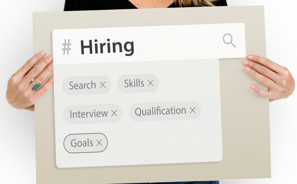 Une personne tenant un panneau montrant une barre de recherche d'emploi avec des étiquettes : Recherche, Compétences, Entretien, Qualification et Objectifs.