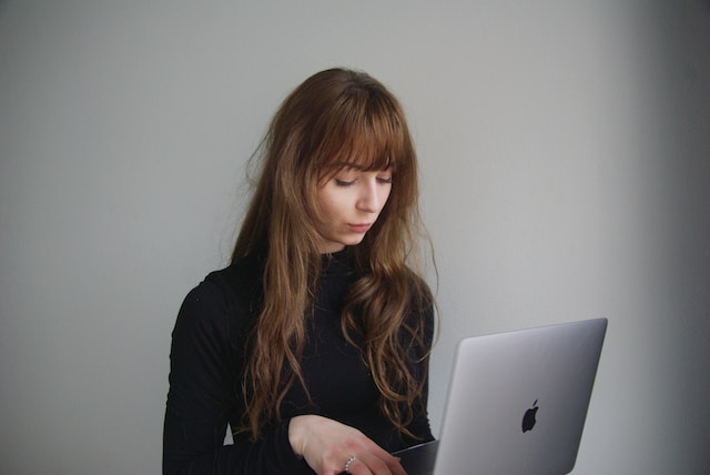 A woman using her laptop to log out of Twitter.