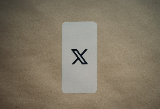 A picture of a black X logo on a white card placed on brown paper.
